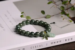 Close-up of deep green jade bead bracelet with a PiXiu pendant on a magazine background