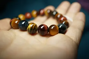 Macro di perle naturali di occhio di tigre rosso blu e giallo su bracciale elastico