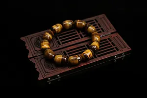 Macro detail of natural tiger eye stone barrel beads with cat eye effect on wood box