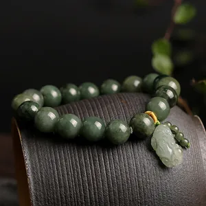 Natural green jadeite bead bracelet with carved Pixiu charm on a dark ceramic surface