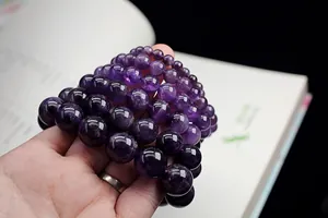 Close-up of multiple purple dream amethyst bead bracelets in various sizes on hand