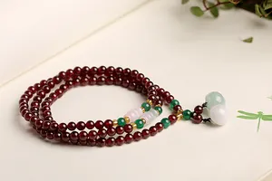 Makro-Detail von mehrlagigem Granat-Perlenarmband mit Jade-Akzenten und Gold-Abstandhaltern