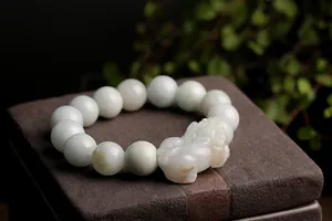 Macro detail of hand-carved jade Pixiu charm and smooth natural beads on a bracelet