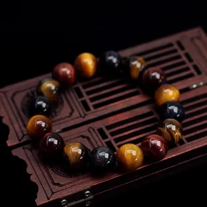 Bracciale in pietre naturali occhio di tigre rosso, blu e giallo su scatola di legno vintage
