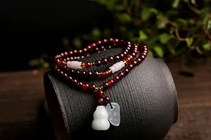 Details von tiefroten Granatperlen mit grünem Jade-Wu-Lou und goldenen Zwischenperlen