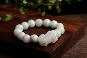 Close-up of a natural jade PiXiu bracelet with polished round beads and detailed carving