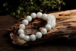 Macro shot of natural jade beads and PiXiu charm on textured wood for Zen-style bracelet