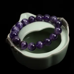 Natural amethyst beaded bracelet with 10mm round crystals on a green ceramic dish