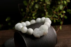 Macro shot of natural green jadeite Pixiu bracelet with polished round beads on a ceramic pot