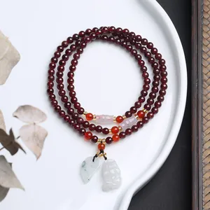 Detailansicht eines 5mm Granat-Perlenarmbands mit Jade-Blattanhänger und Schnitzereien