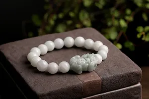 Macro shot of natural jade beads bracelet with detailed hand-carved Pixiu charm on stone