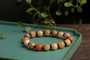 Detail of carved lotus Gobi jade beads in diverse colors on a teal ceramic plate