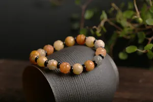 Macro shot of natural quartz bracelet with pumpkin-shaped carved beads on ceramic cup