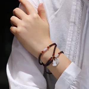 Mehrlagiges Granat-Perlenarmband mit Jade-Hülsenfrucht-Anhänger am Handgelenk