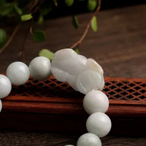 Natural jadeite Pi Xiu bracelet with light green round beads on a vintage wooden desk