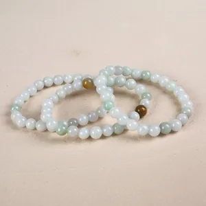 Close-up of three natural jade bead bracelets in pale green and white with amber accents