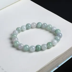 Close-up of green and lavender natural jadeite beads on a minimalist book background