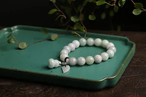 Detailed shot of natural jade beads with Pixiu and gourd charms on a vintage plate