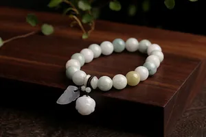 Detail of natural jade bead bracelet with leaf pendant on wooden display stand