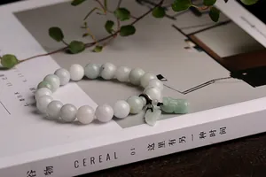 Detailed shot of natural jade bead bracelet with hand-carved Pixiu charm on Cereal magazine