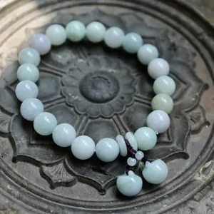 Macro shot of natural green jadeite beads and mini apple pendants on a carved stone plate