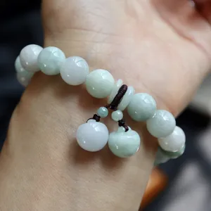 Close-up of natural jade beads bracelet with apple charms and peace buckle on wrist