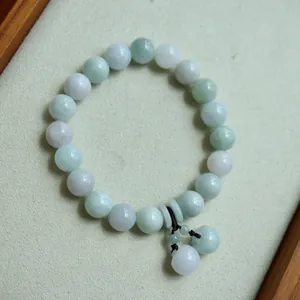 Detail of natural green jade beaded bracelet with a safety buckle pendant on a tray