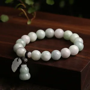 Natural jade bead bracelet with gourd pendant on a dark wooden display stand