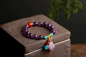 Detailweergave van amethist kralenarmband met rode agaatkraal en kristallen hanger