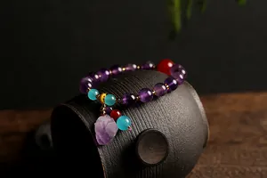 Detail van natuurlijke amethist armband met gouden kralen en ruwe kristallen hanger