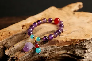Macro-opname van natuurlijke amethist armband met ruwe steen hanger op oud hout