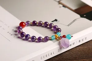 Detail van natuurlijke amethist armband met paarse kralen en ruwe stenen hanger