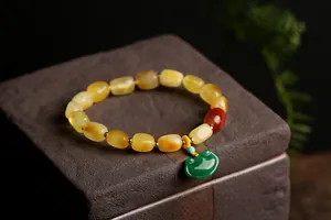 Detailed close-up of natural amber bead bracelet with a green jade ruyi lock pendant