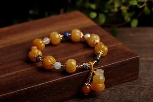 Detailed view of yellow pumpkin beads and gourd charm on an ethnic gemstone bracelet