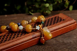 Close-up of ethnic beaded bracelet with yellow pumpkin beads and a small gourd charm