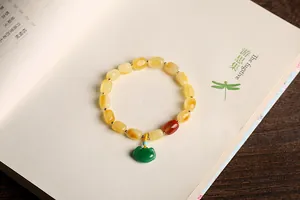 Close-up of amber beads with green ruyi pendant and golden spacers on a book