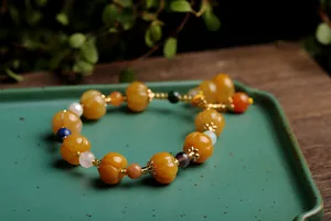 Macro detail of pumpkin-shaped yellow beads and colorful gemstones on a silk jade bracelet