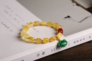 Detailed shot of amber beaded bracelet with green jade lock on a white magazine