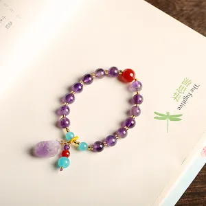 Natuurlijke paarse amethist kralenarmband met ruwe stenen hanger op een boek