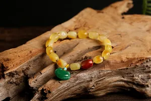 Detail of beeswax beaded bracelet with green jade-style lock charm on wood