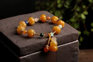 Close-up of golden jade pumpkin beads bracelet with small gourd pendant and enamel flower