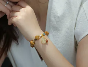 Detailed view of yellow gold silk jade bracelet with pumpkin beads and gourd charm