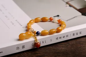 Detail of yellow agate beaded bracelet with gourd pendant on a magazine page
