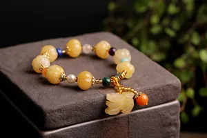 Close-up of golden jade pumpkin beads and PiXiu pendant on a vintage ethnic bracelet