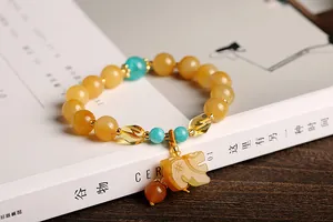Detailed shot of yellow gemstone beaded bracelet with a cat pendant on a magazine