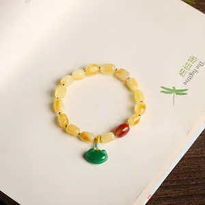 Natural amber bead bracelet with green jadeite Ruyi lock pendant on vintage book