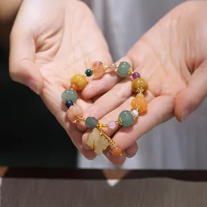 Macro shot of colorful stone beads featuring pumpkin carvings and a yellow jade pendant