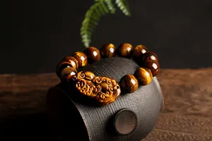 Detalle macro de cuentas de ojo de tigre natural y dije Pi Xiu tallado en una pulsera