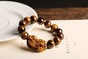 Detalle macro de cuentas de ojo de tigre natural y pulsera con amuleto Pixiu tallado