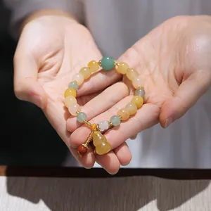Close-up of multicolor gemstone bead bracelet featuring yellow gourd and golden spacers